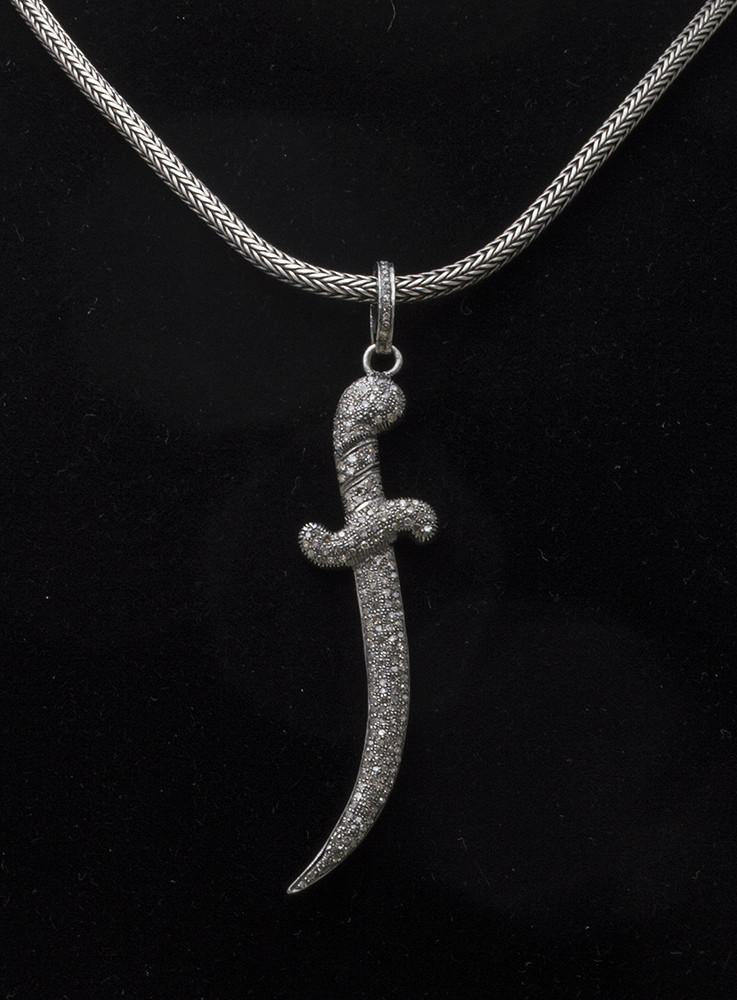Large diamond encrusted curved dagger pendant on chain.